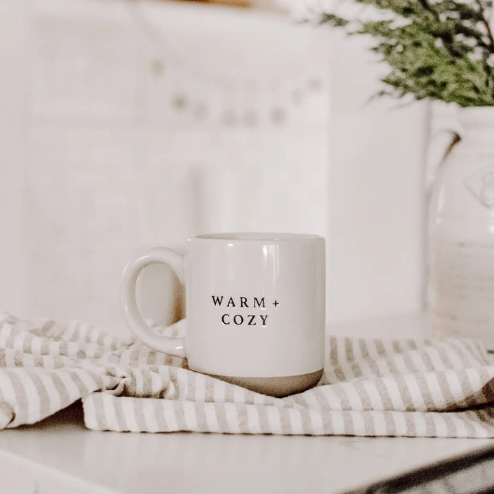 Sweet Water Decor Warm and Cozy Kaffeetasse auf auf Esstisch, daneben eine Decke – gemütliche Szene
