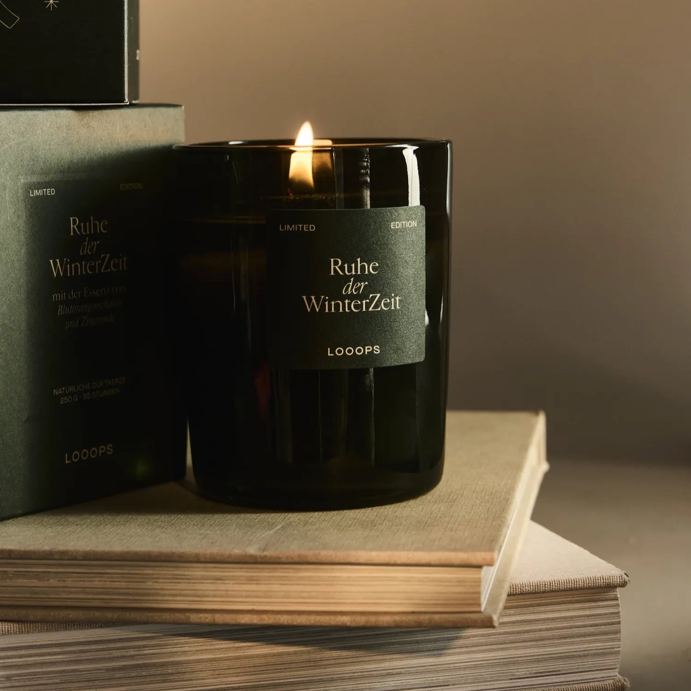 LOOOPS Kerze "Ruhe der Winterzeit" auf Büchern stehend.