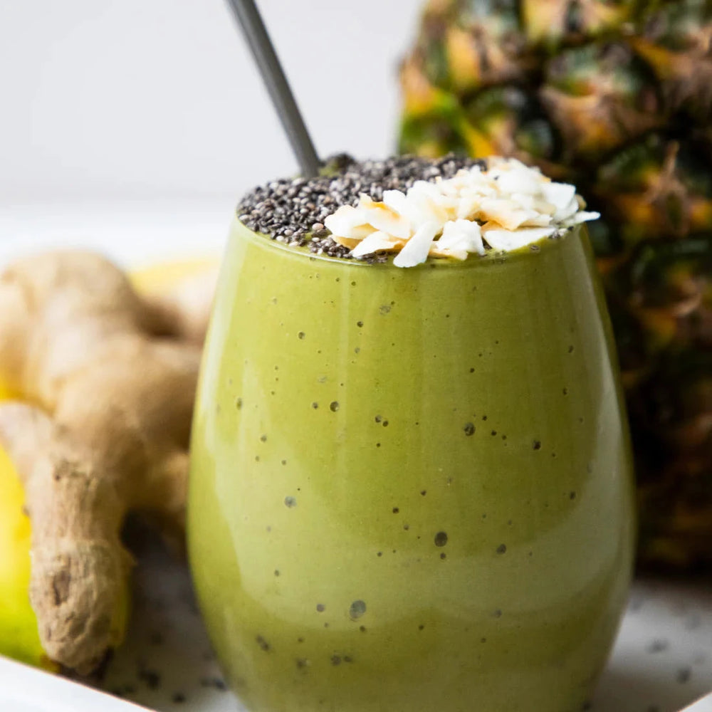 KIANO Matcha Power Latte mit Chiasamen und Blüte vor Ingwer und Ananas