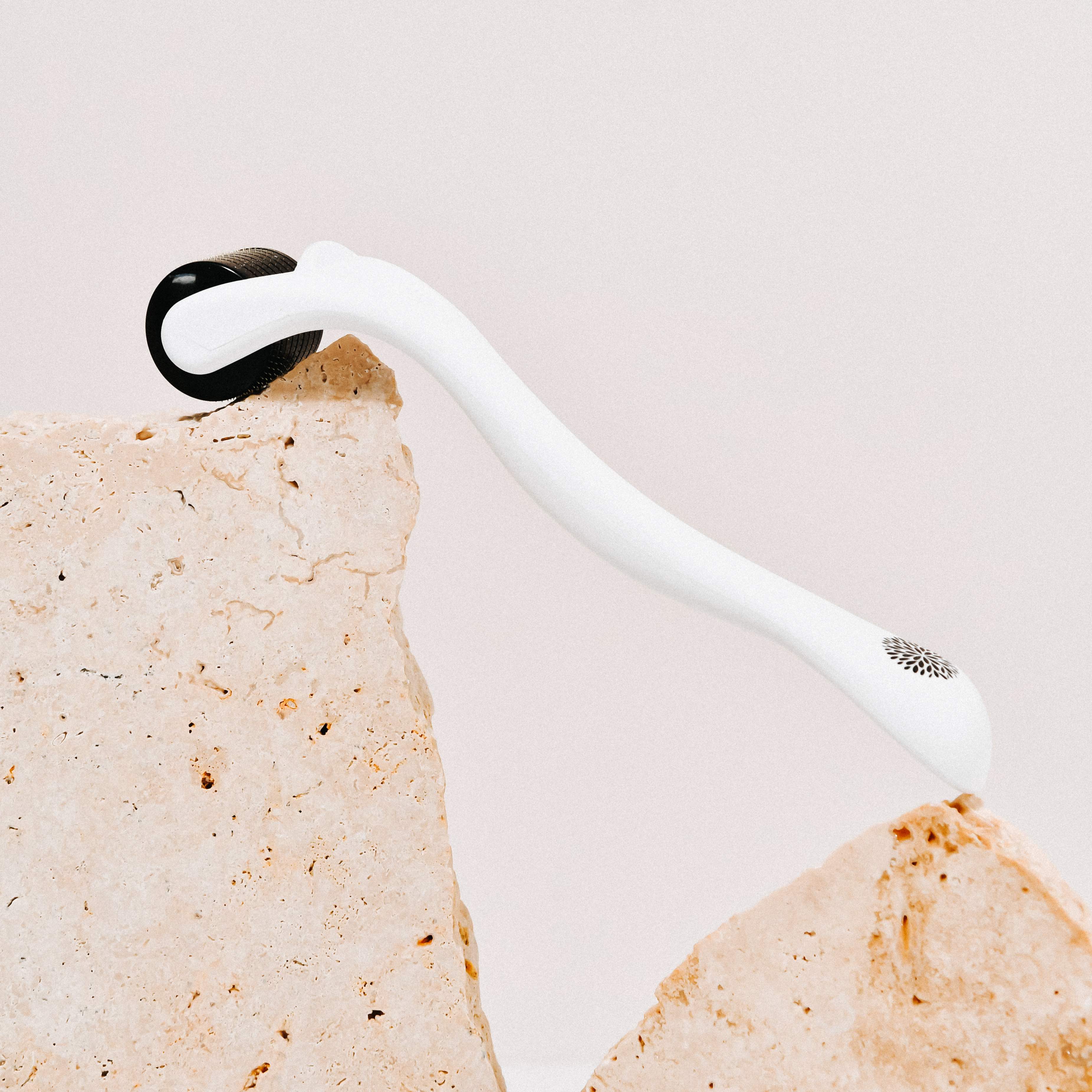 Wildcrafted Organics Microneedle Dermal Roller liegt liegt auf einer Steinplatte.