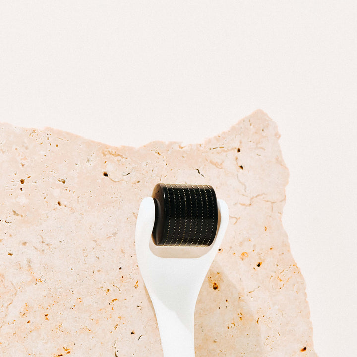 Nahaufnahme des Wildcrafted Organics Microneedle Dermal Rollers auf einer Steinplatte.