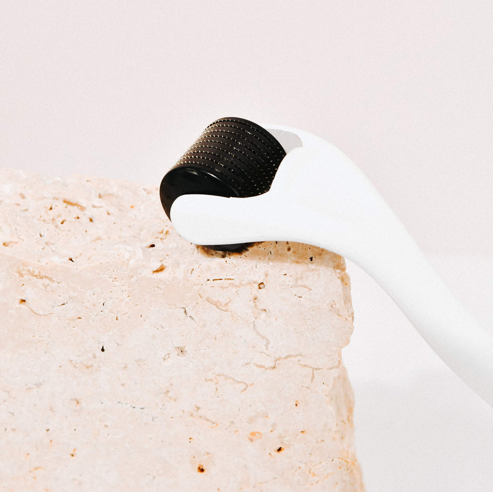 Wildcrafted Organics Microneedle Dermal Roller liegt liegt auf einer Steinplatte.