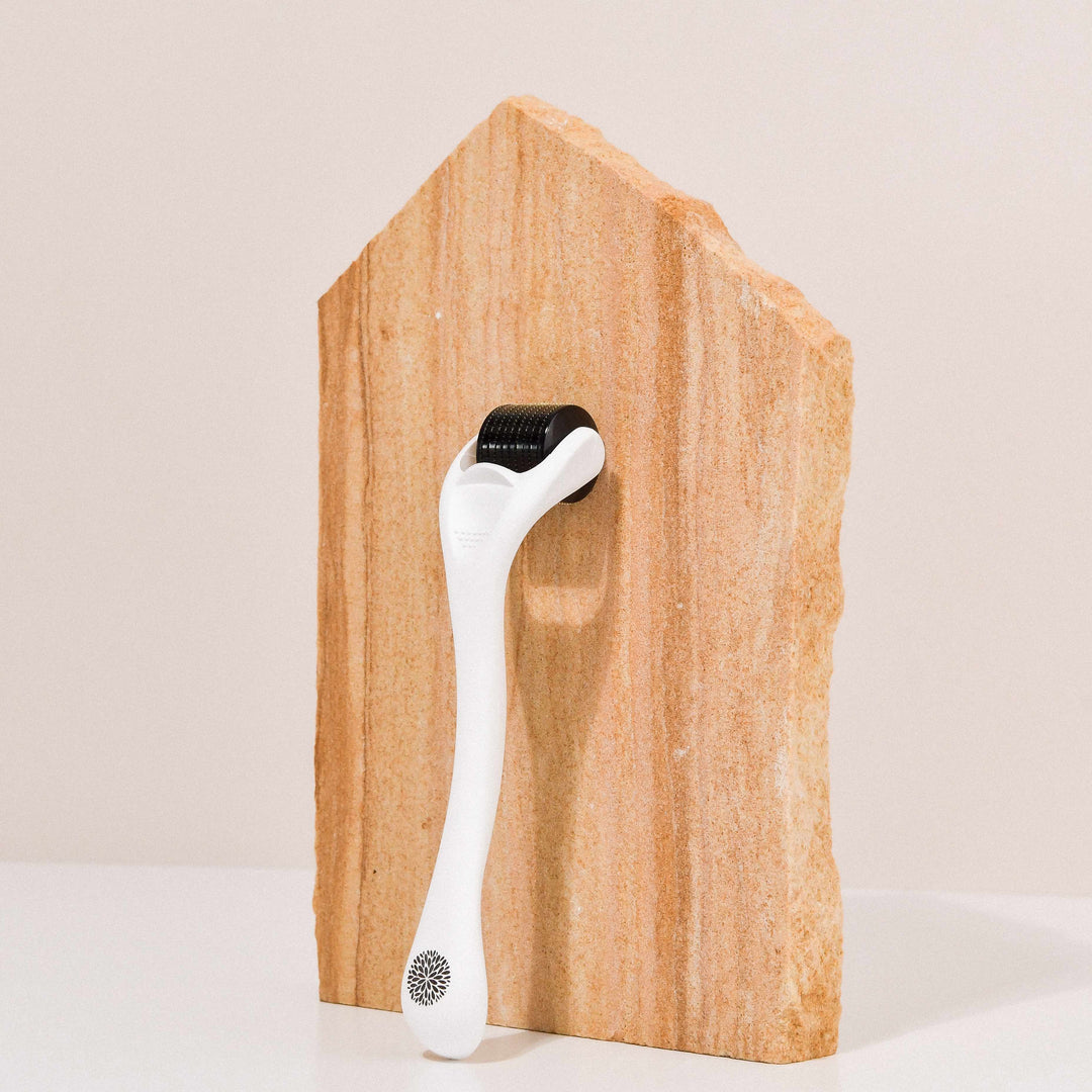 Wildcrafted Organics Microneedle Dermal Roller liegt lehnt an einer Steinplatte. North Glow