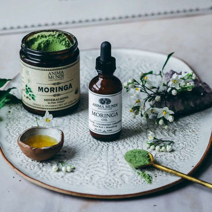Glasflasche Moringa Oil von Anima Mundi, daneben ein Glas mit Moringapulver.