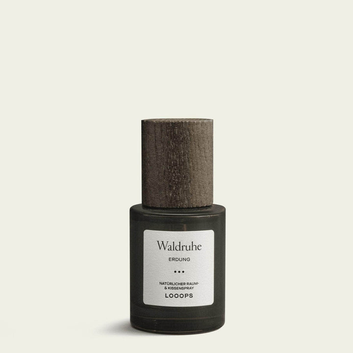 Flasche Waldruhe Raum- und Kissenspray von Looops mit Holzdeckel steht vor weißem Hintergrund.