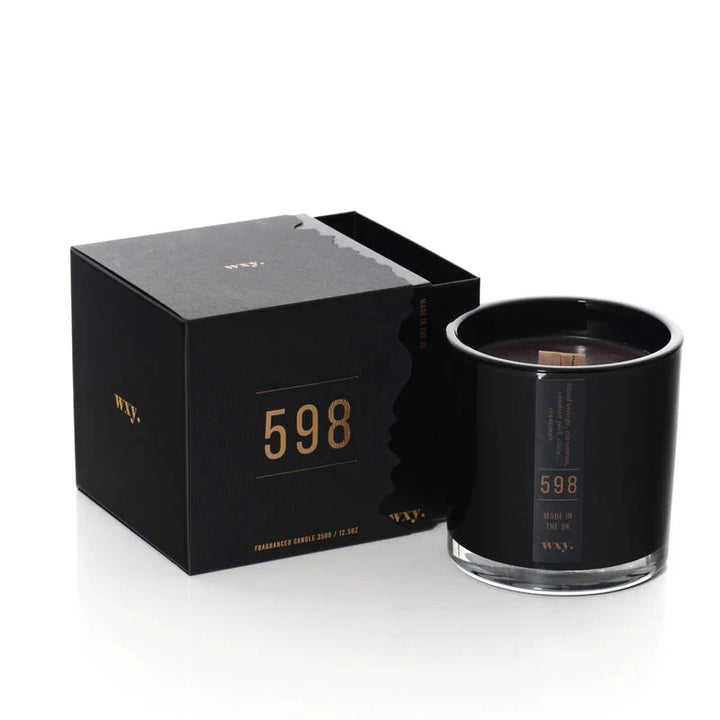 Schwarze wxy. Kerze mit Verpackung vor weißem Hintergrund.