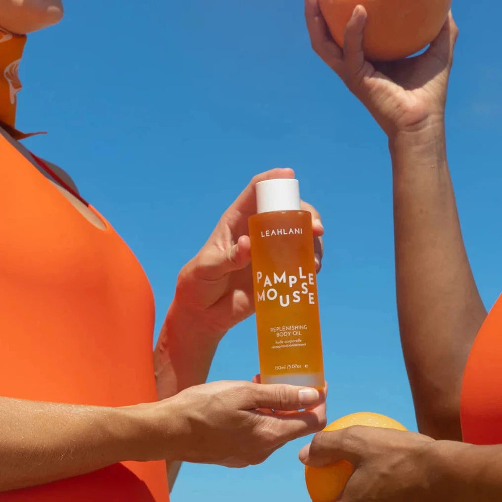 Leahlani Pamplemousse Body Oil wird von zwei Händen gehalten. 