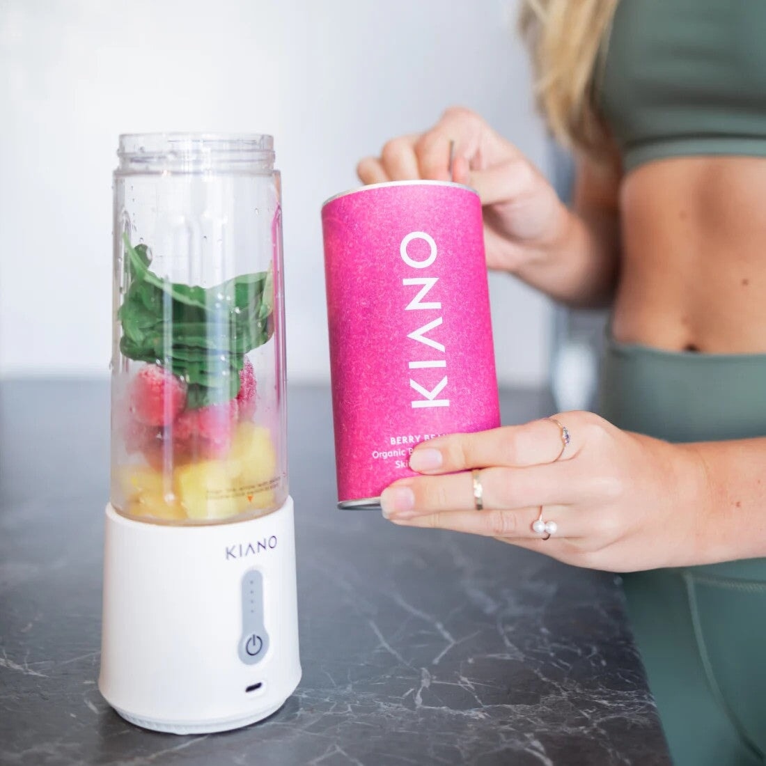 Kiano Portable Blender steht offen auf einem Tisch, gefüllt mit Beeren, Obst und Blattgemüse.