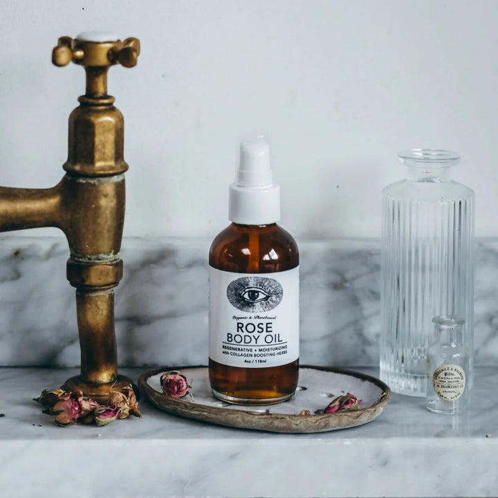 Flasche Rose Body Oil auf Marmorplatte  im Bad mit Blüten.