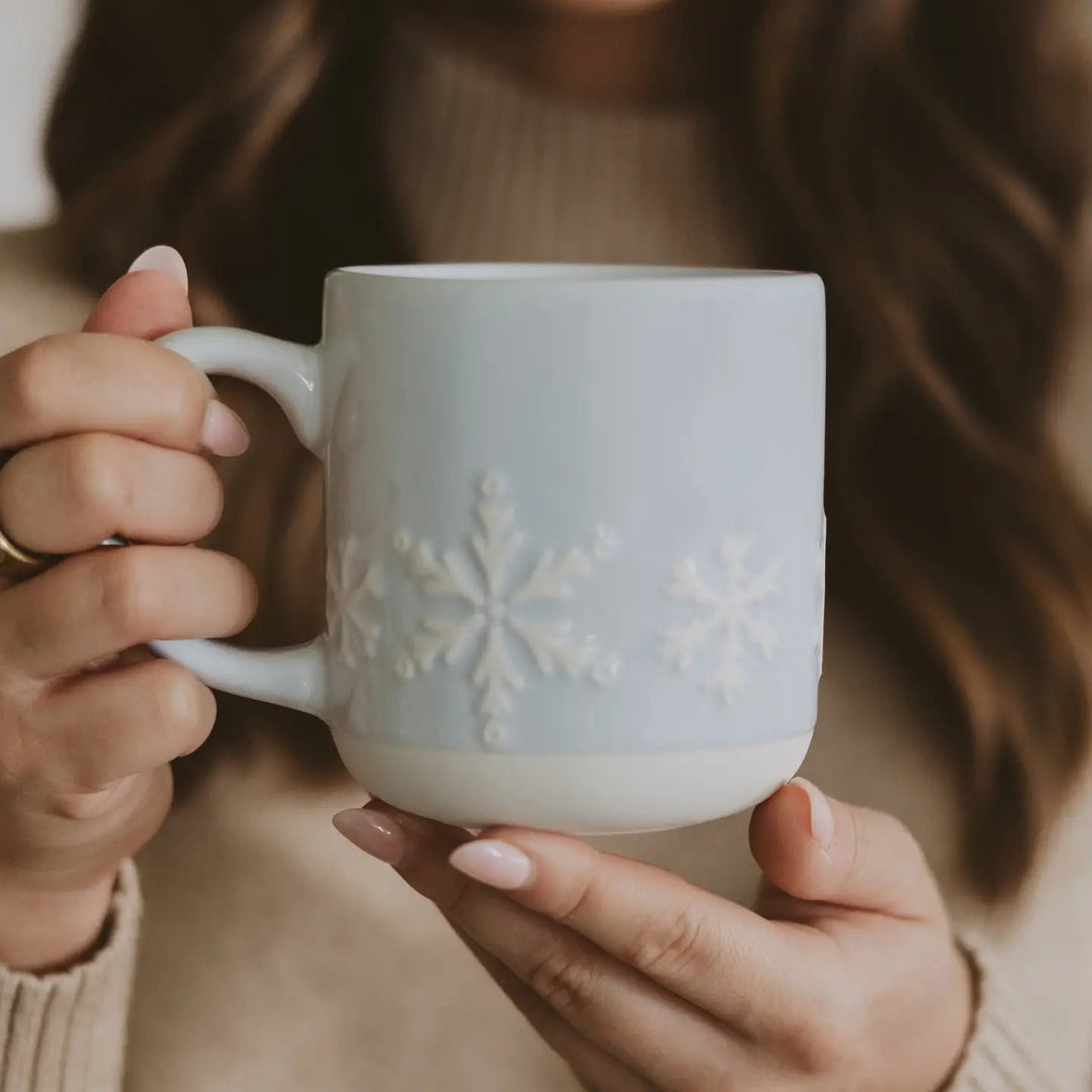 Schneeflocken Tasse von Frauenhänden gehalten – hellblaue Keramik mit winterlichem Design North Glow