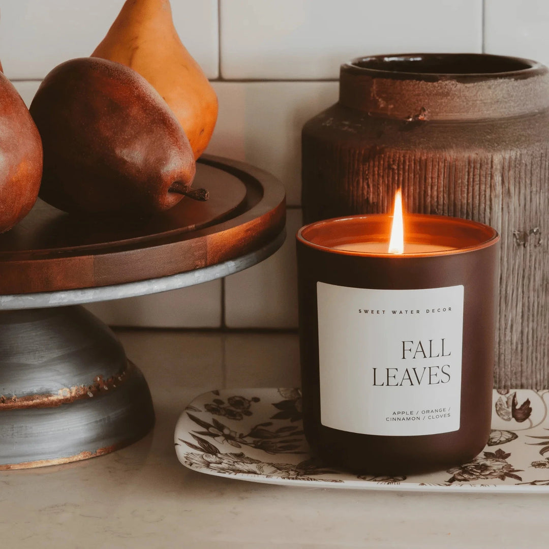 Gemütliche Küchenszene mit brennender Fall Leaves Sojawachskerze von Sweet Water Decor und reifen Birnen.