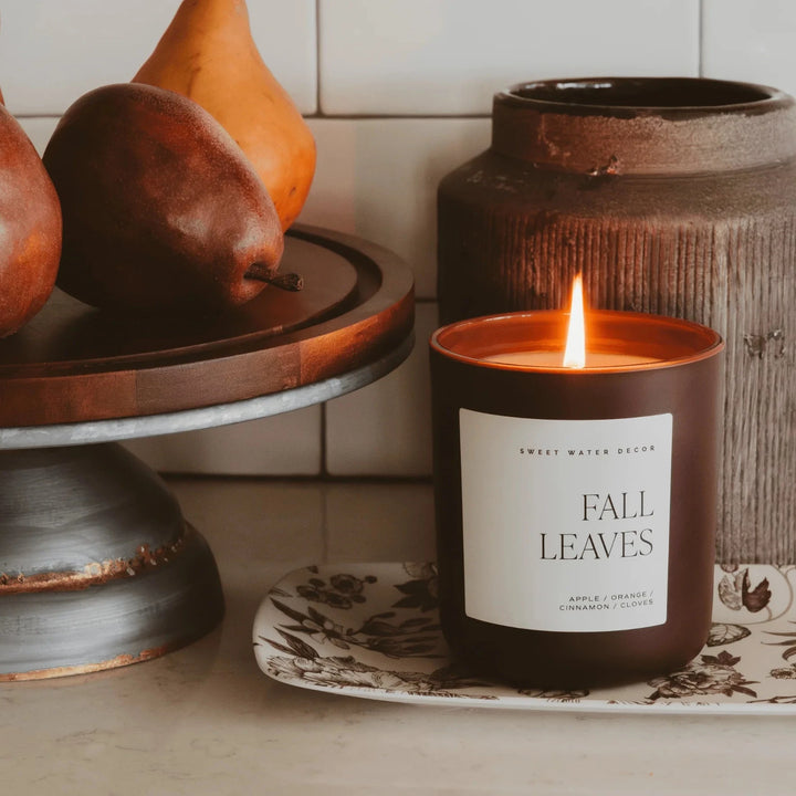 Gemütliche Küchenszene mit brennender Fall Leaves Sojawachskerze von Sweet Water Decor und reifen Birnen.