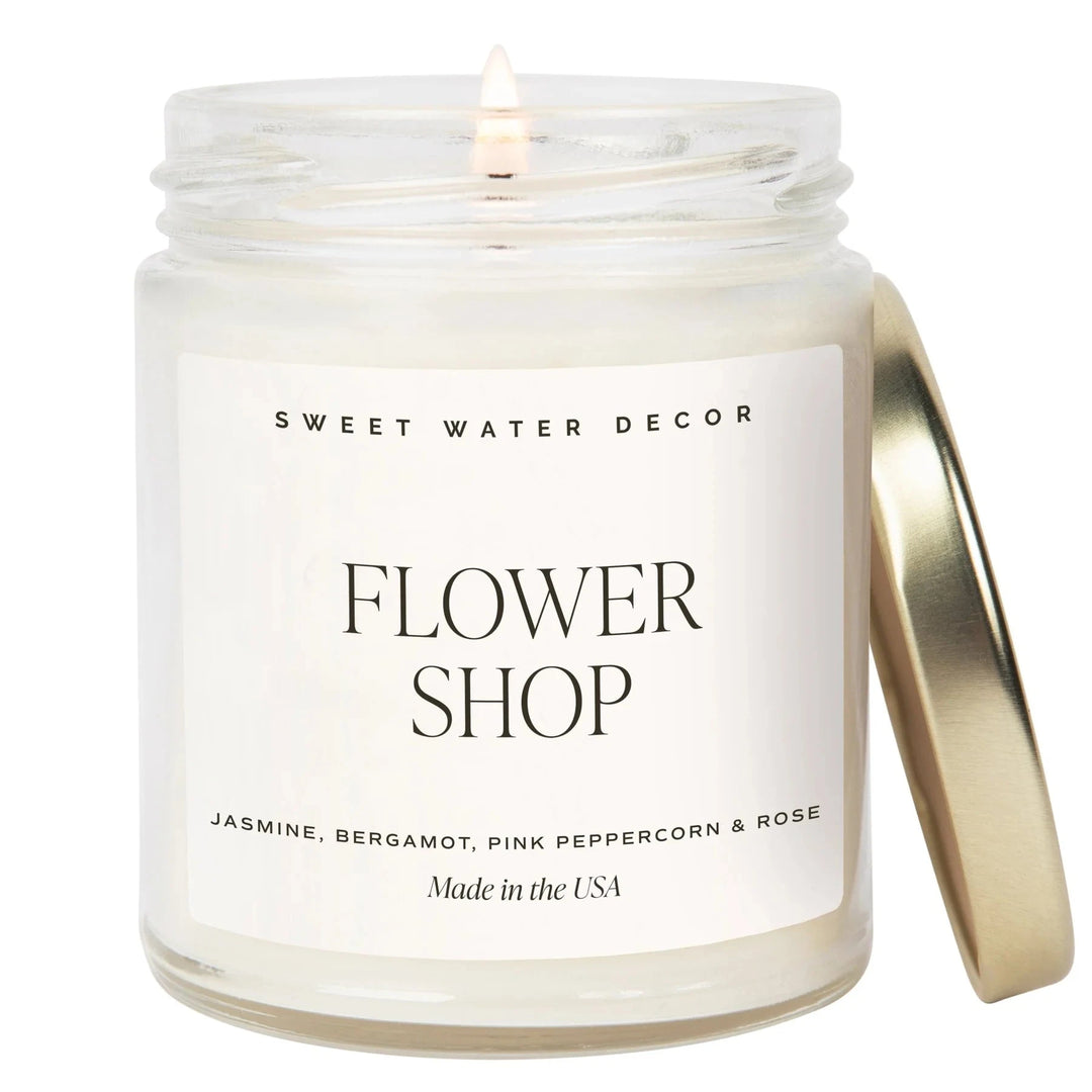 Brennnende Kerze Flower Shop von Sweet Water Decor steht vor weißem Hintergrund. North Glow