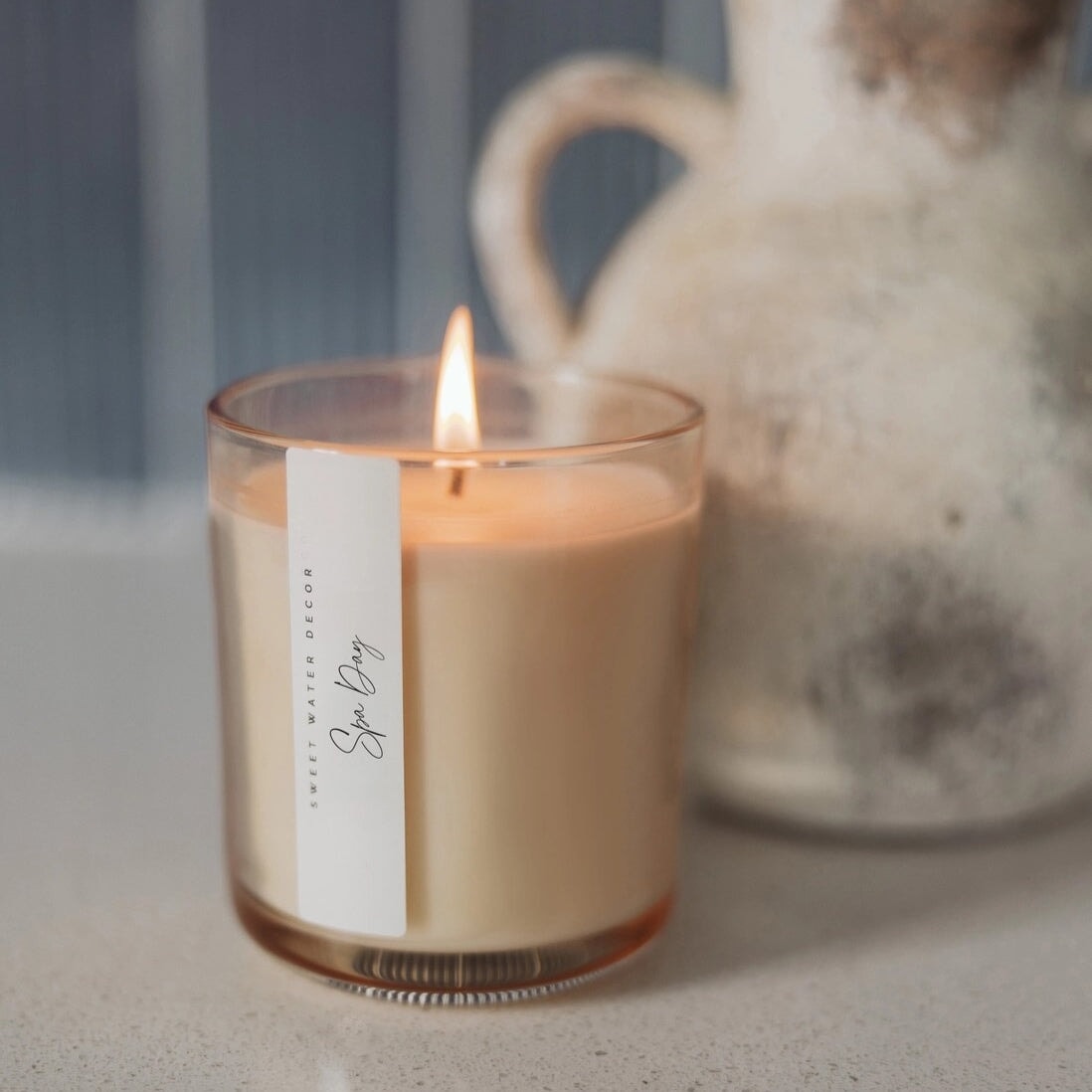 Brennende Sweet Water Decor Duftkerze Spa Day im getöntem Glas mit Aufschrift in Schreibschrift.