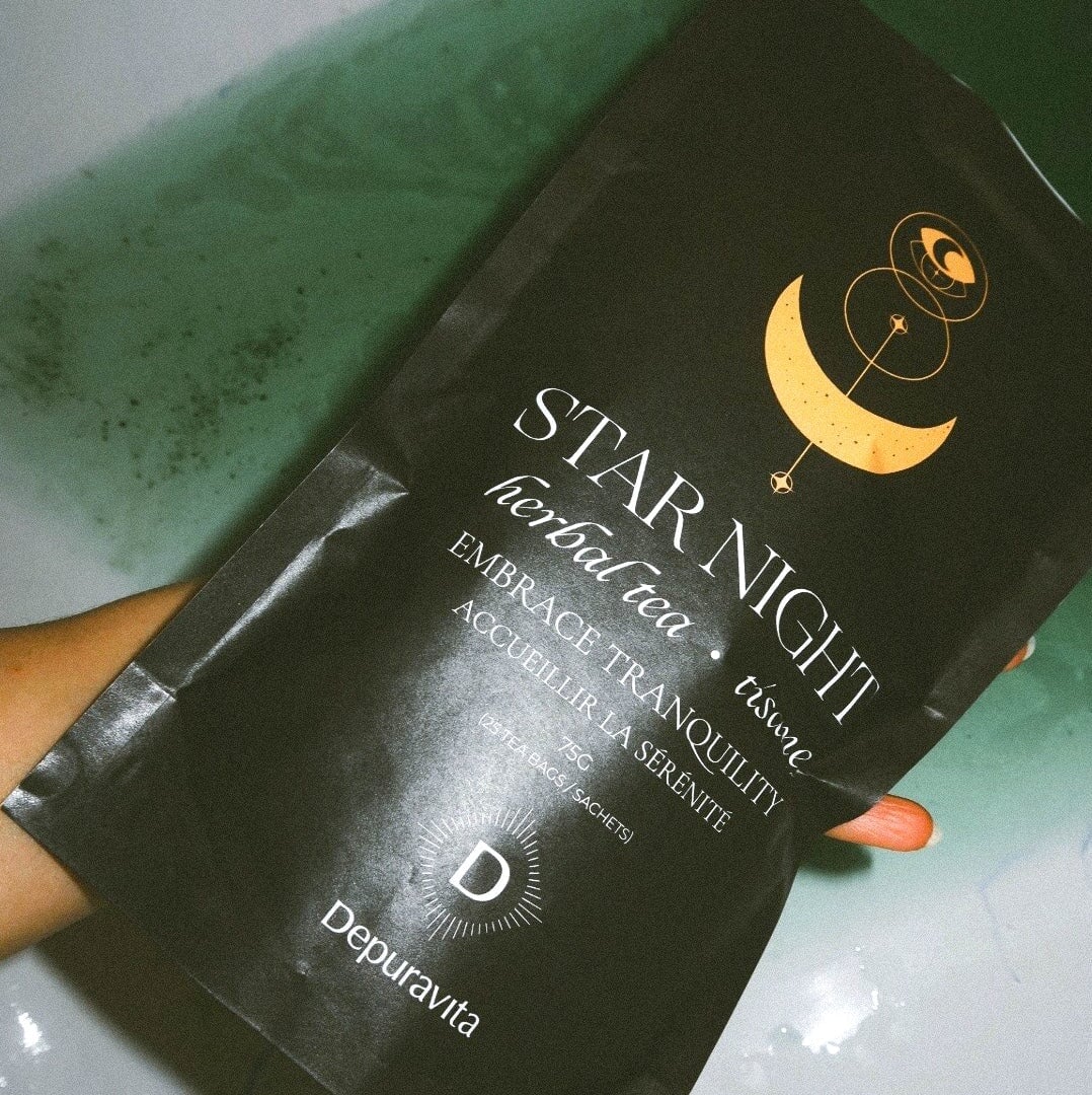 Depuravita Star Night Teepackung von einer Hand gehalten vor grünem Hintergrund. 