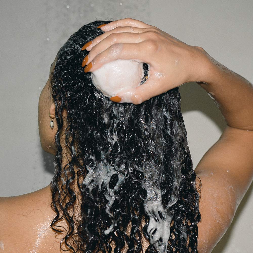 Anwendung des festen Shampoos – Frau wäscht sich die Haare mit Super Soft Hair Wash + Balm.