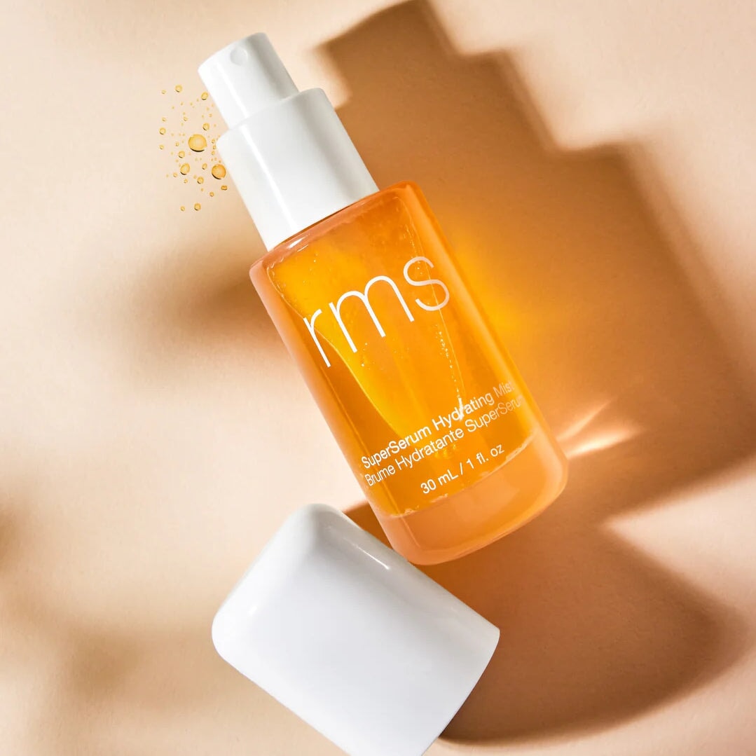 Offene Pumpsprayflasche SuperSerum Hydrating Mist von RMS liegt neben dem Deckel auf hellem Untergrund.