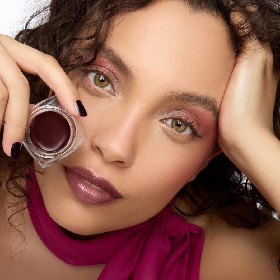 Eine Frau hält den Lippenbalm COLOMBA in ihrer Hand vors Gesicht.