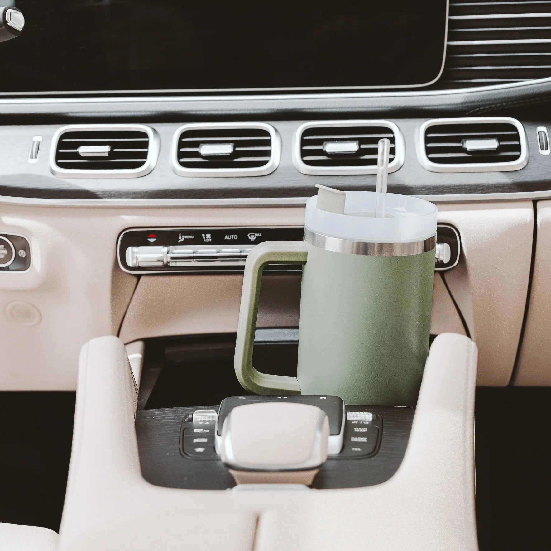 Grüner Tumbler / Thermobecher von Sweet Water Decor steht in der Mittelkonsole eines Autos.