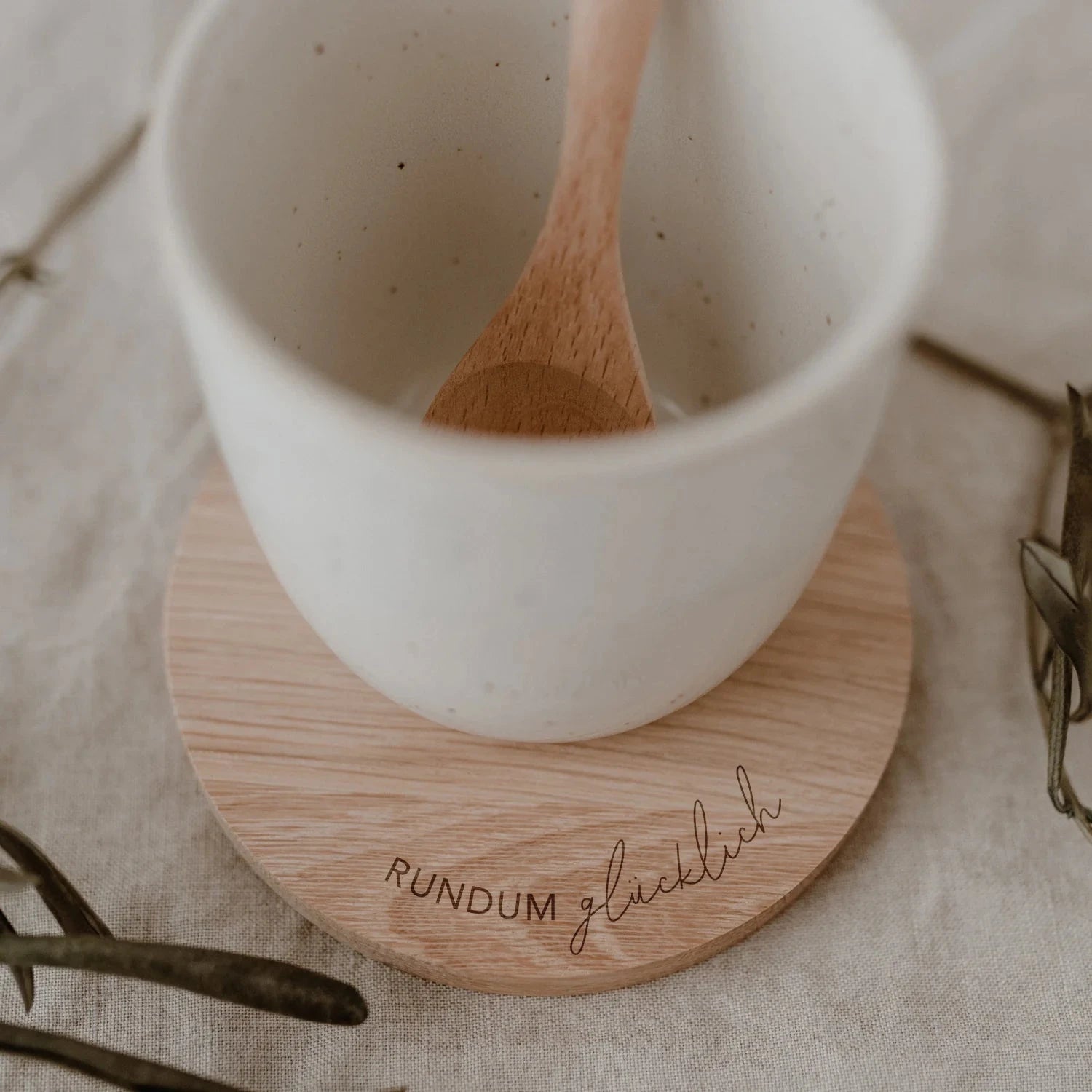 Untersetzer RUNDUM glücklich von Eulenschnitt, darauf eine Tasse mit Holzlöffel.