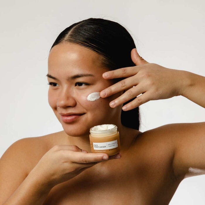 Frau trägt  UpCircle Moisturiser auf Wange auf – strahlende, gepflegte Haut, intensive Feuchtigkeit und Vitamin‑E‑Schutz.