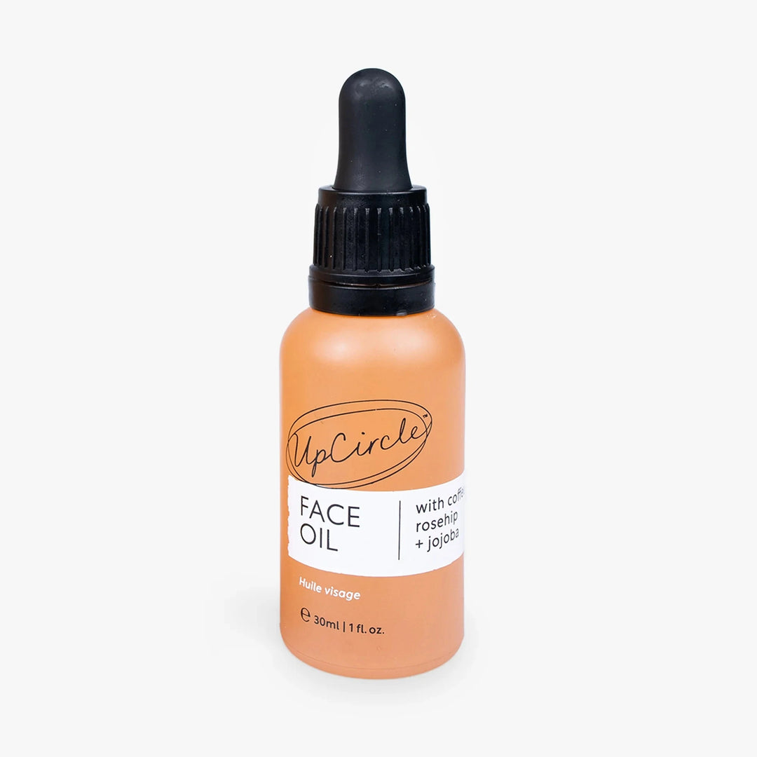 Orangefarbene Glasflasche mit Pipette des Gesichtsöls von UpCircle Beauty vor weißem Hintergrund 