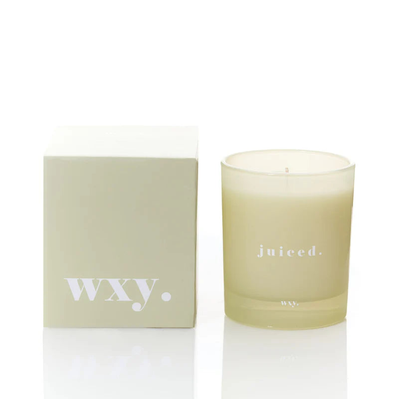 Kerze juiced von wxy. in cremefarbenem Glas, daneben die Produktverpackung.