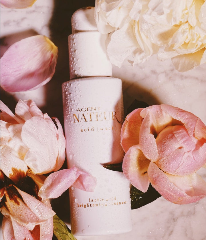 Agent Nateur Acid Wash Flasche auf weißem Marmortisch mit rosa Blüten