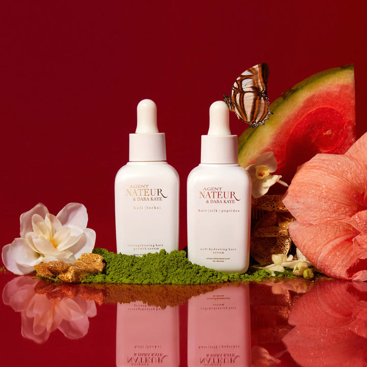 Agent Nateur Hair Silk Peptides Flasche mit aufgeschnittener Melone, Schmetterling und Blüten vor rotem Hintergrund