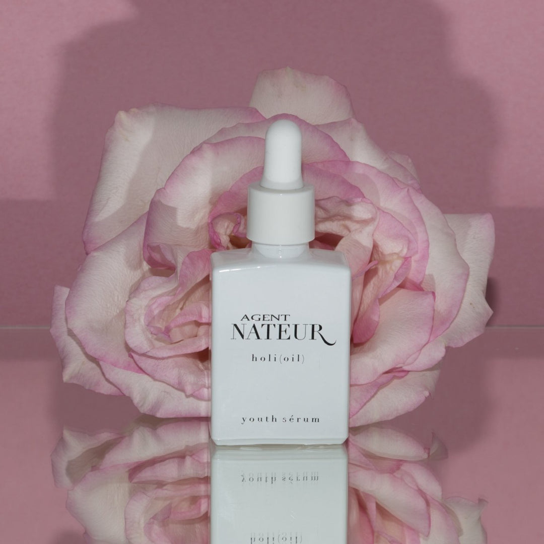 Agent Nateur Holi (Oil) weißer Flakon vor rosa Rose und rosa Hintergrund North Glow