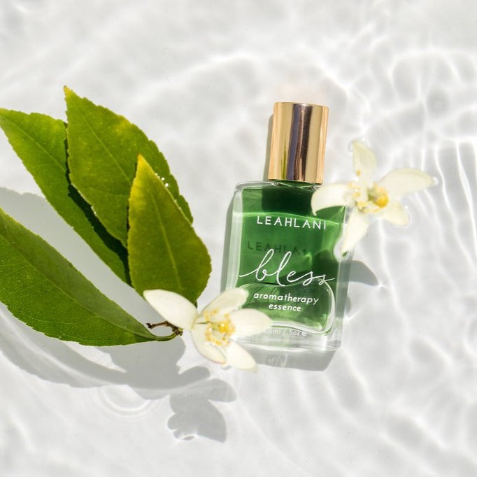 Leahlani Bless Aromatherapy Essence Flakon mit grünen Blättern und weißen Blüten im Wasser
