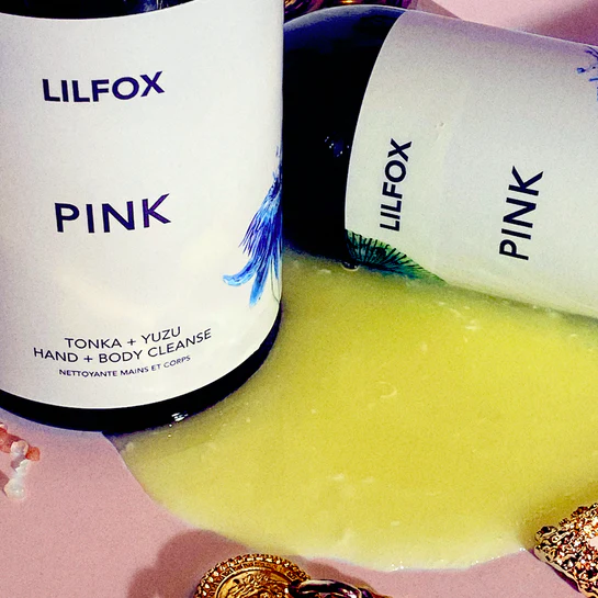 Lilfox Pink Flasche mit gelber Textur und Schmuck im Hintergrund