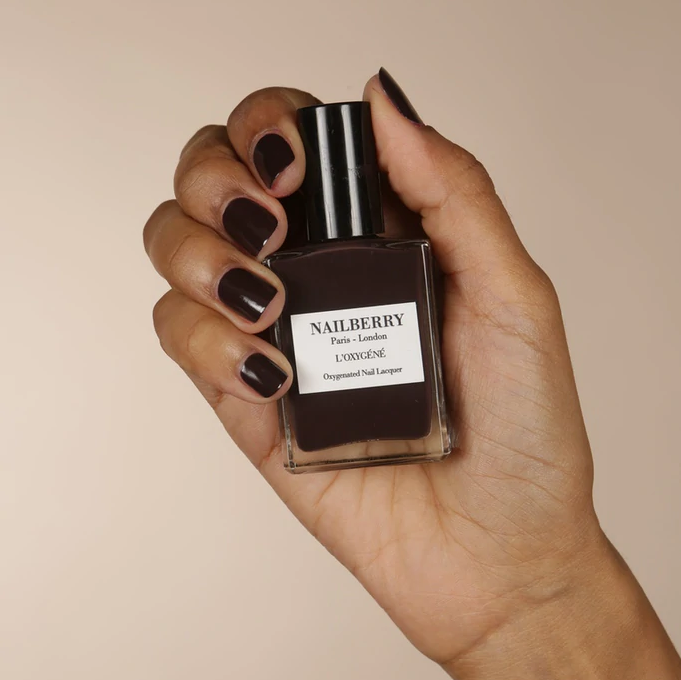 Hand hält Nagellackflasche Nailberry Hot Coco. North Glow