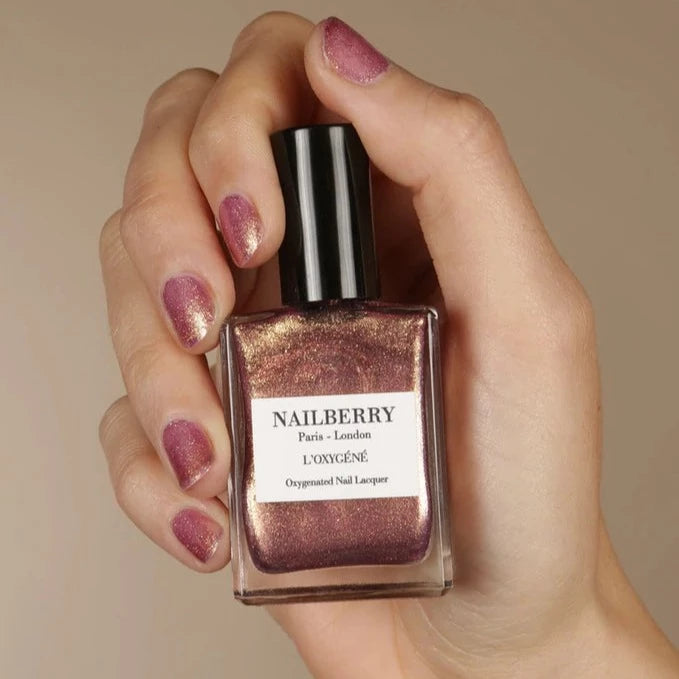 Hand hält Nailberry Nagellackflasche Pink Sand. North Glow