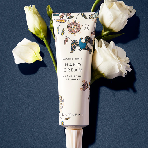 Ranavat Sacred Rose Hand Cream mit weißen Blüten auf blauem Hintergrund