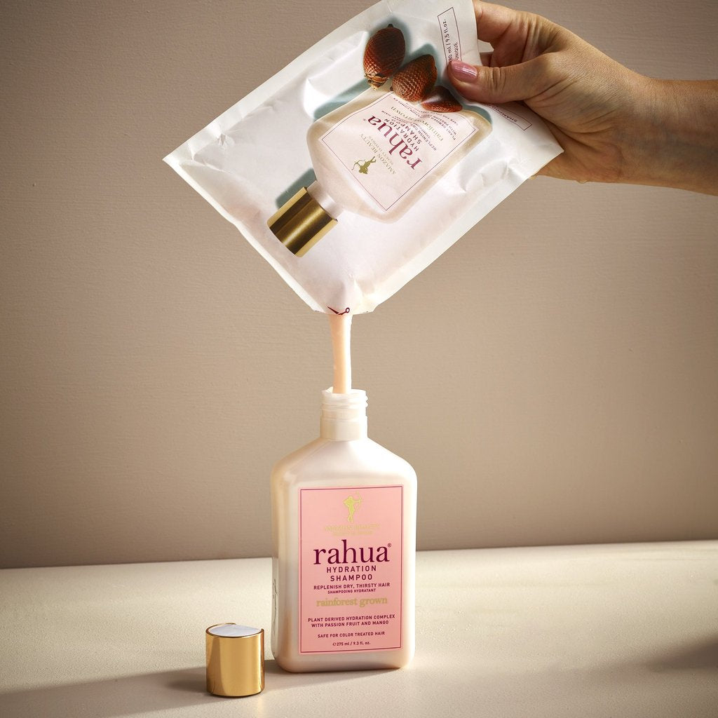 Hand hält Rahua Hydration Shampoo Refillpouch in der Hand und füllt Inhalt in die Flasche um. North Glow