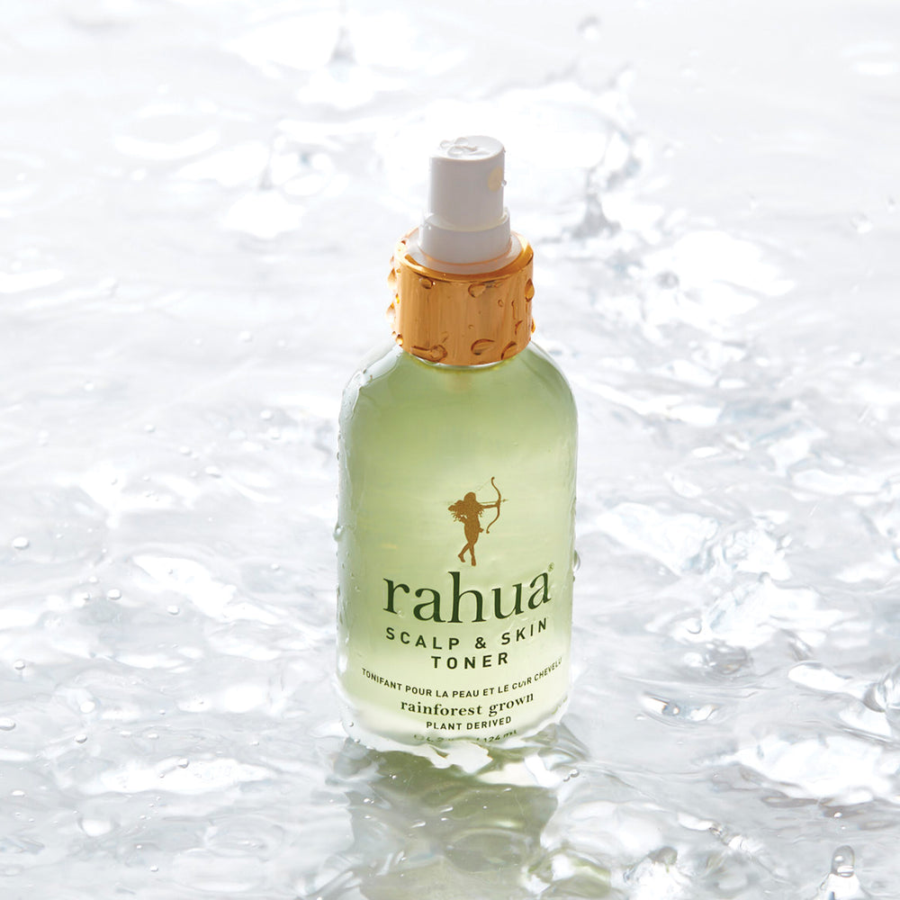 Nasse Rahua Scalp & Skin Toner Flasche steht im Wasser vor hellem Hintergrund.