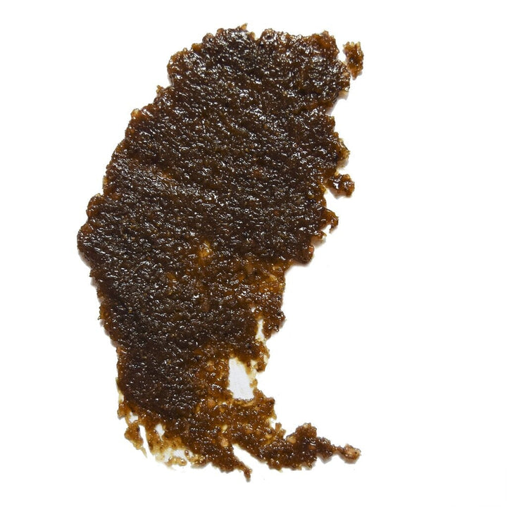 Texturbeispiel von dem UMA Absolute Anti Aging Body Scrub - eine glänzende, körnige, dunkelbraune Masse.