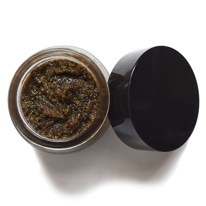 Aus der Vogelperspektive sieht man ein offenes UMA Absolute Anti Aging Body Scrub Schraubglas mir einer körnigen, braunen Masse.