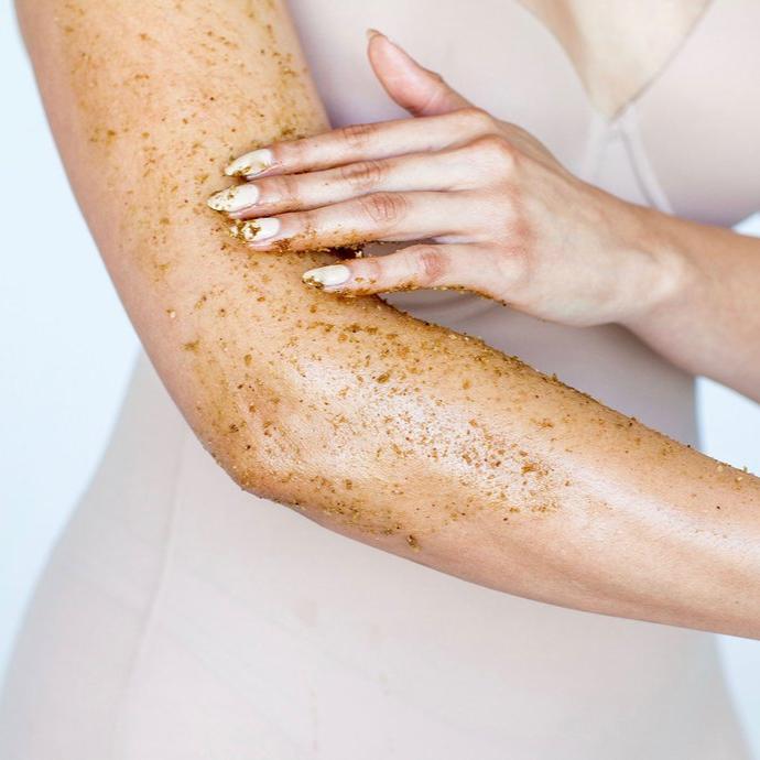 UMA Absolute Eine Frau schmiert sich mit dem Anti Aging Body Scrub den Oberarm ein.
