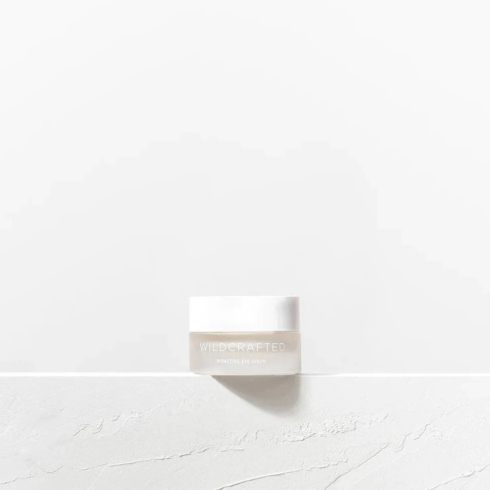 Milchglastiegel mit weißem Deckel Wildcrafted Bioactive Eye Serum steht auf einer weißen Steinplatte. North Glow