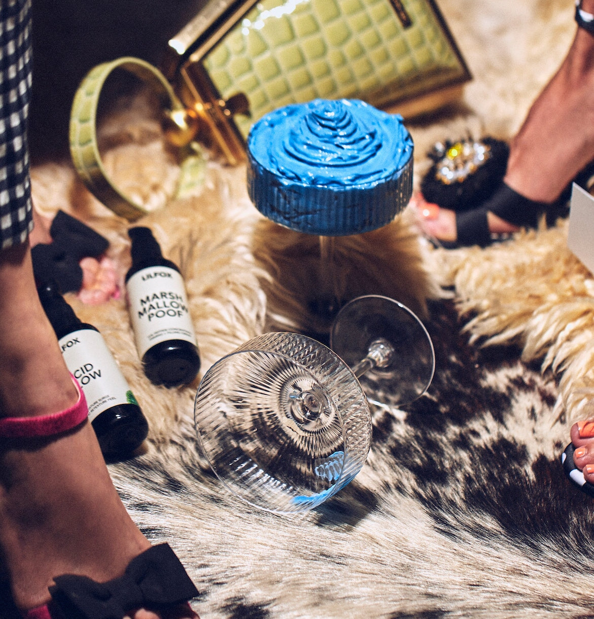 Blue Legume in Sektkelch auf Schaffell mit Handtasche im Hintergrund