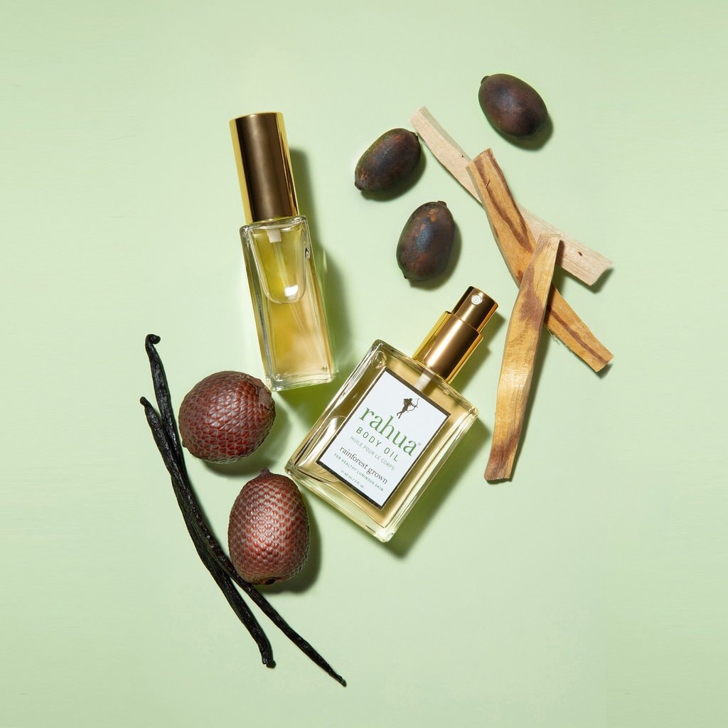 2 Rahua Body Oil Flaschen vor hellgrünem Hintergrund, dekoriert mit Zimt, Palo Santo, Rahuanuss.