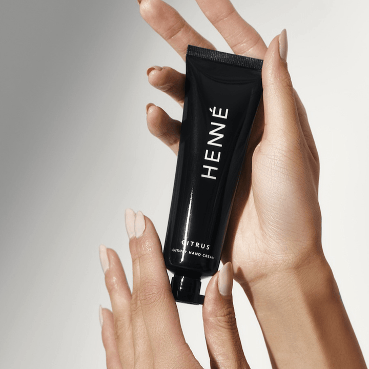 2 gepflegte Hände halten eine Henné Organics Tube Handcreme Citrus in die Luft.