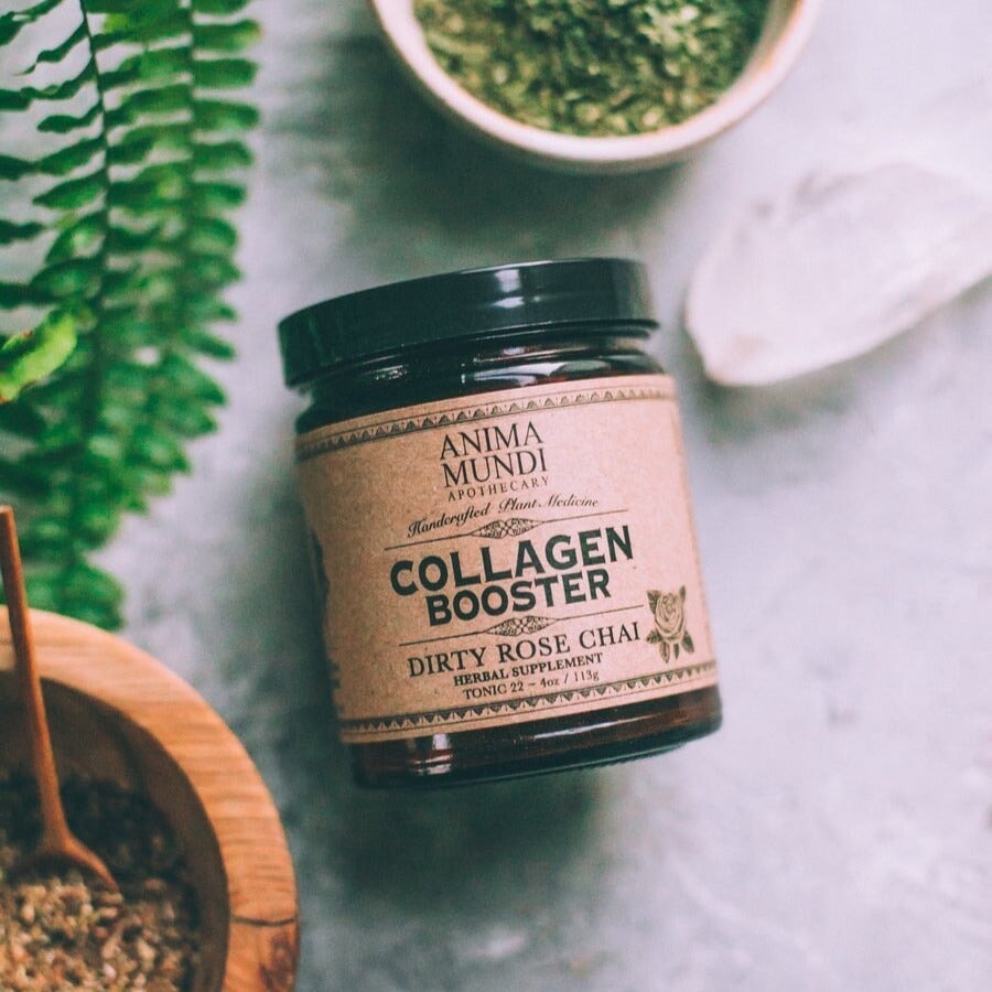 Anima Mundi Collagen Booster Schraubglas liegt zwischen Mörsern mit Kräutern. North Glow