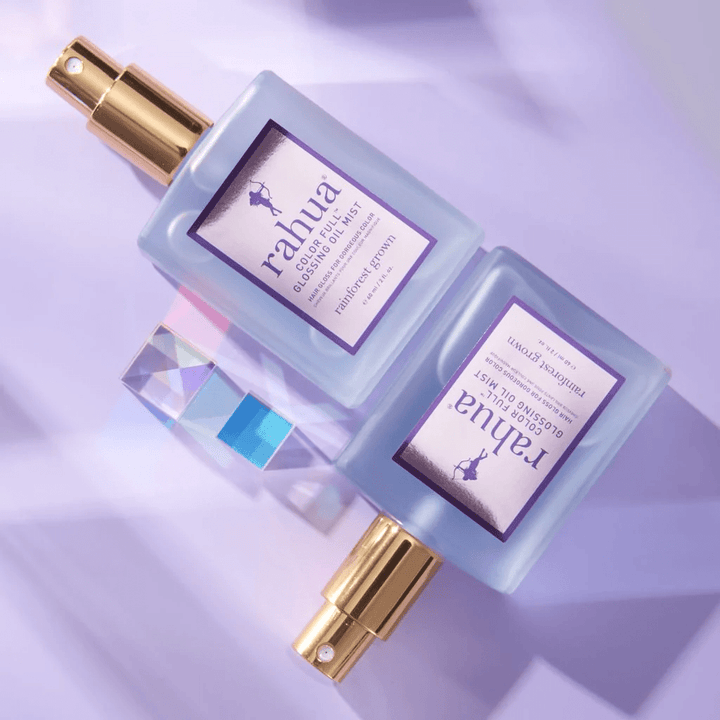2 Rahua Color Full Glossing Oil Mist Flaschen liegen auf lilafarbenem Hintergrund.