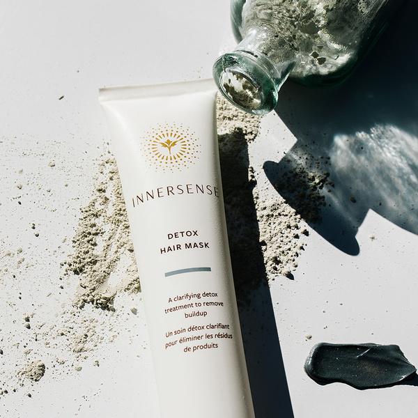 Innersense Detox Hair Mask Tube liegt auf verstreuter pulverisierter Kohle.