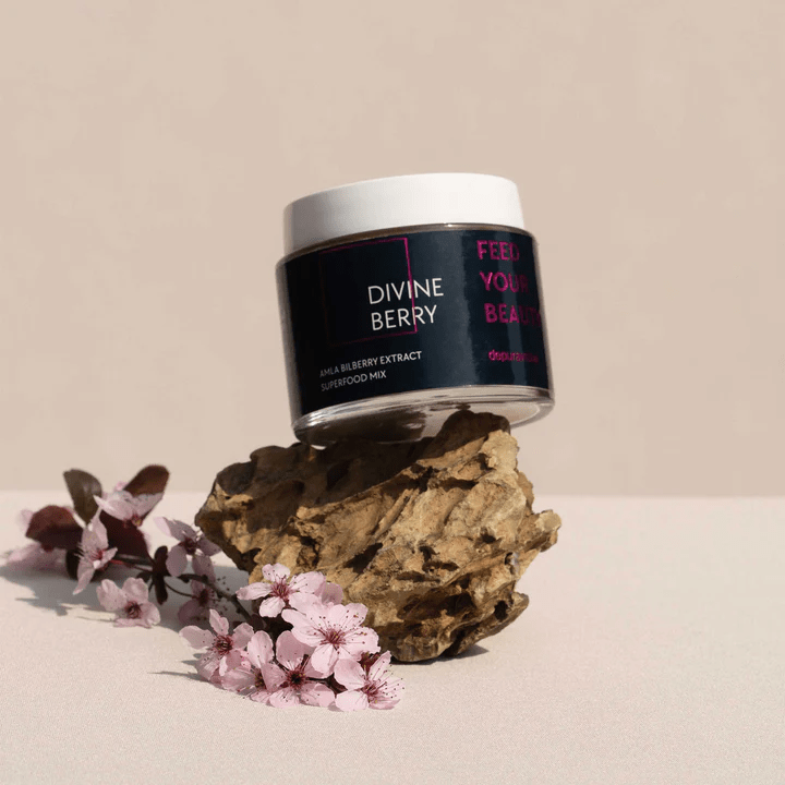 Depuravita Divine Berry Tiegel auf Holz mit rosa Blüten vor hellem Hintergrund