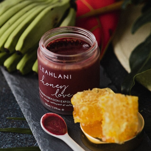 Leahlani Honey Love Exfoliator Tiegel geöffnez mit Honigwabe, Bananen und Löffel auf grauer Schieferplatte