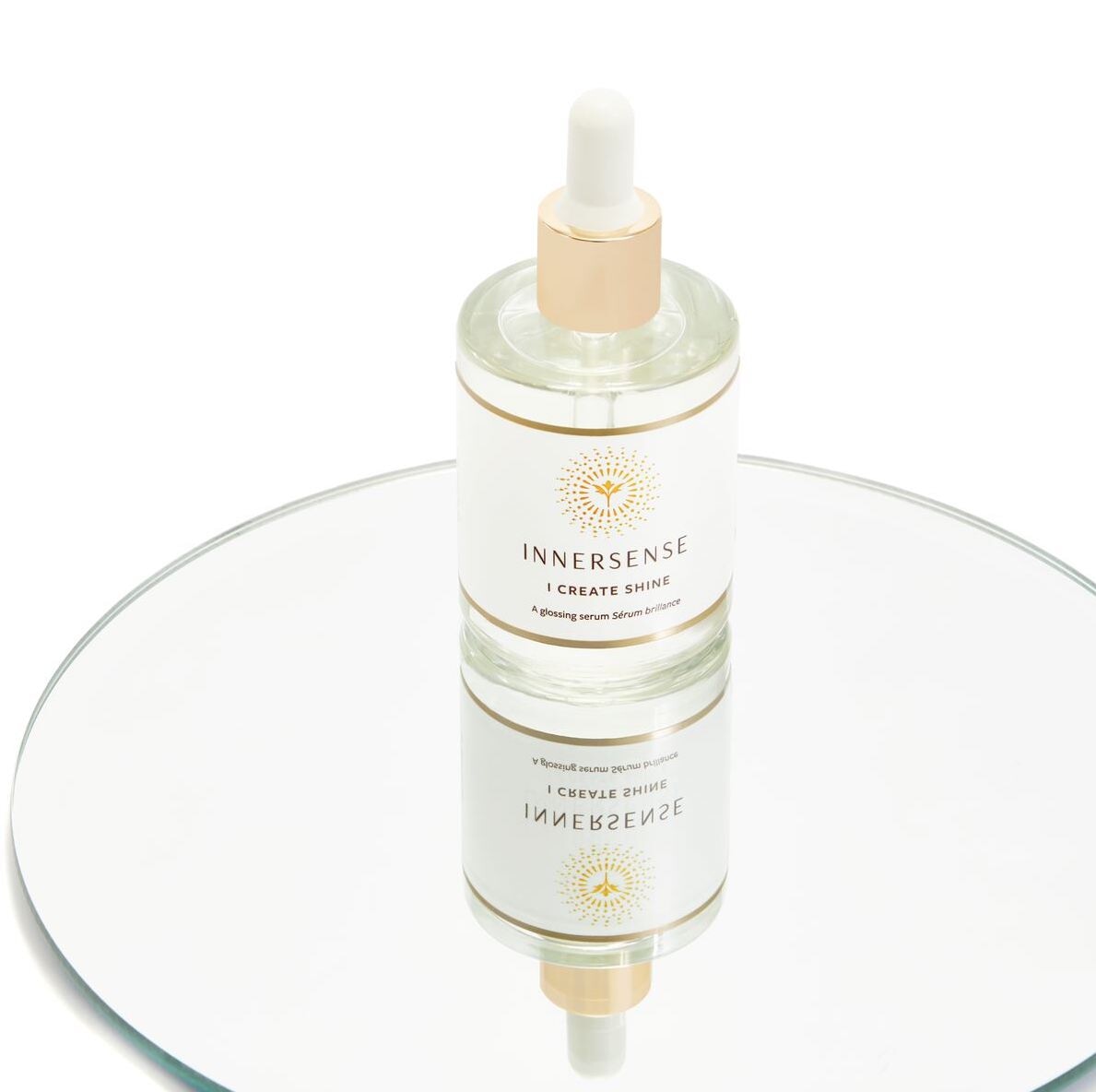 Innersense I Create Shine Pipettenflasche steht auf einem kreisrunden Spiegel.